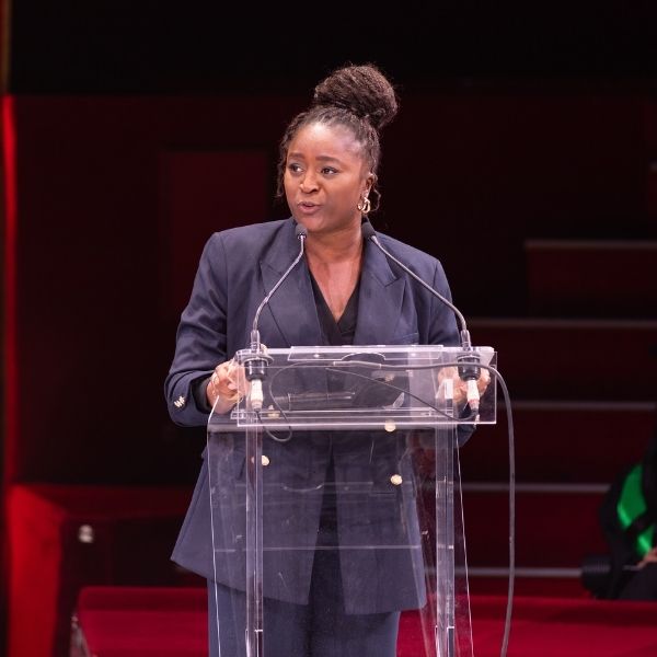 Femme en tenue professionnelle donne un discours dans une salle de spectacle