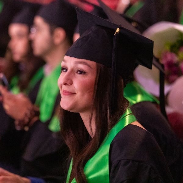 Jeune femme brune en tenue de diplômée lors d'une remise des diplômes